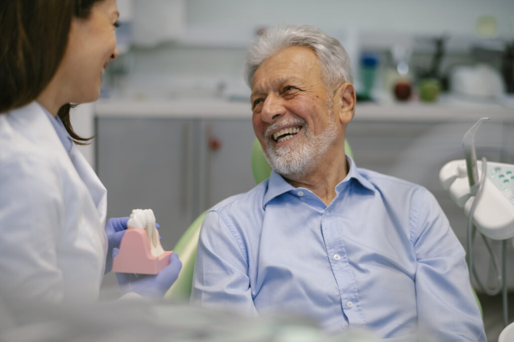 Senior man at the dentist laughing as he and the dentist have conversation